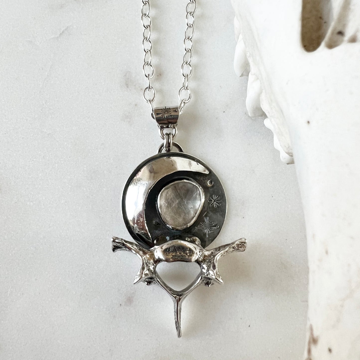 Moon and raccoon vertebra pendant with faceted clear topaz