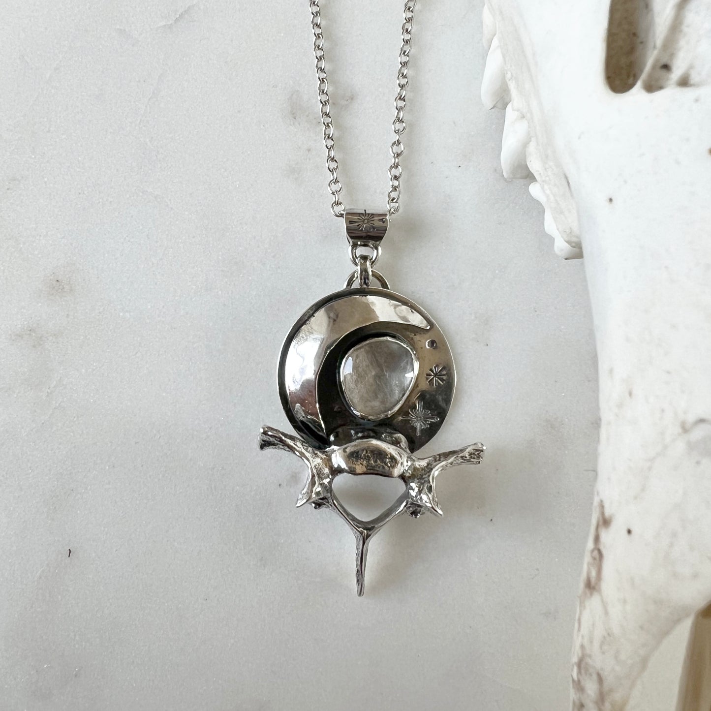 Moon and raccoon vertebra pendant with faceted clear topaz